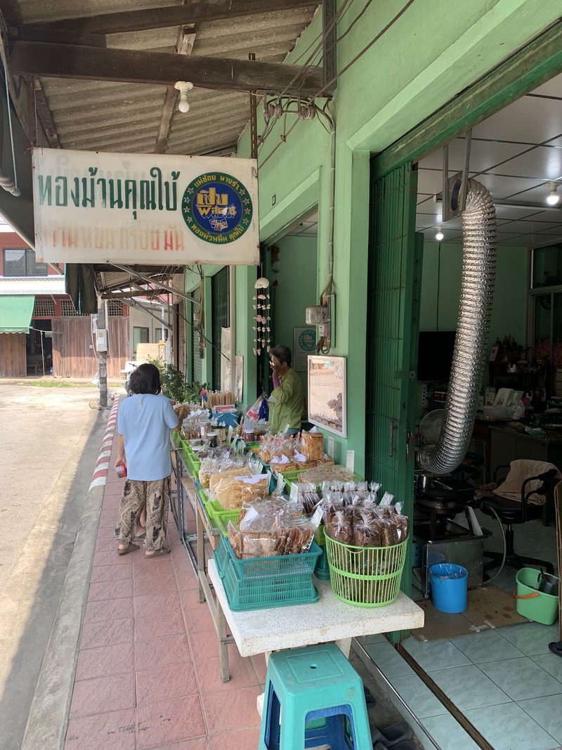 แผงขนมหน้าร้านริมทางเท้า มองเห็นป้ายชื่อร้านทองม้วนคุณใบ้ด้านบน
